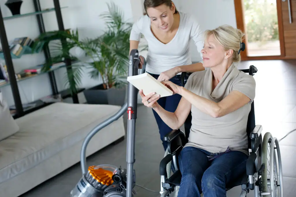 young woman helping disabled lady at home
